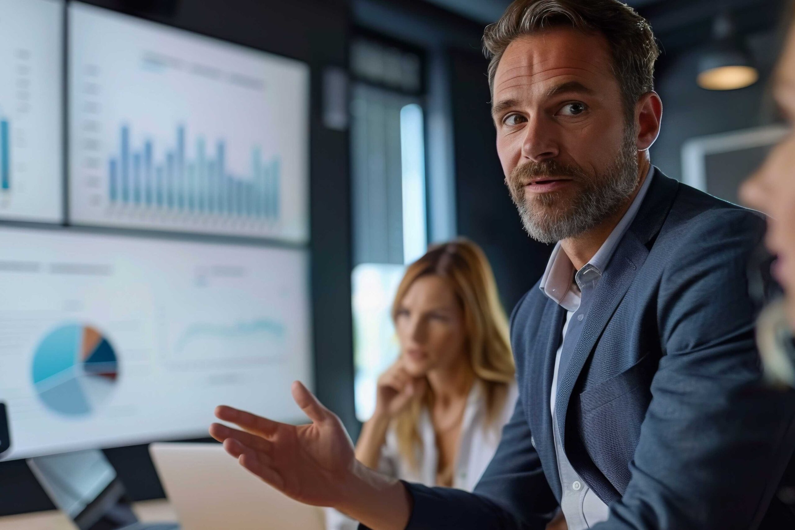 American SurgiSite executive presenting performance metrics during a meeting, with charts and graphs displayed on large screens in the background.