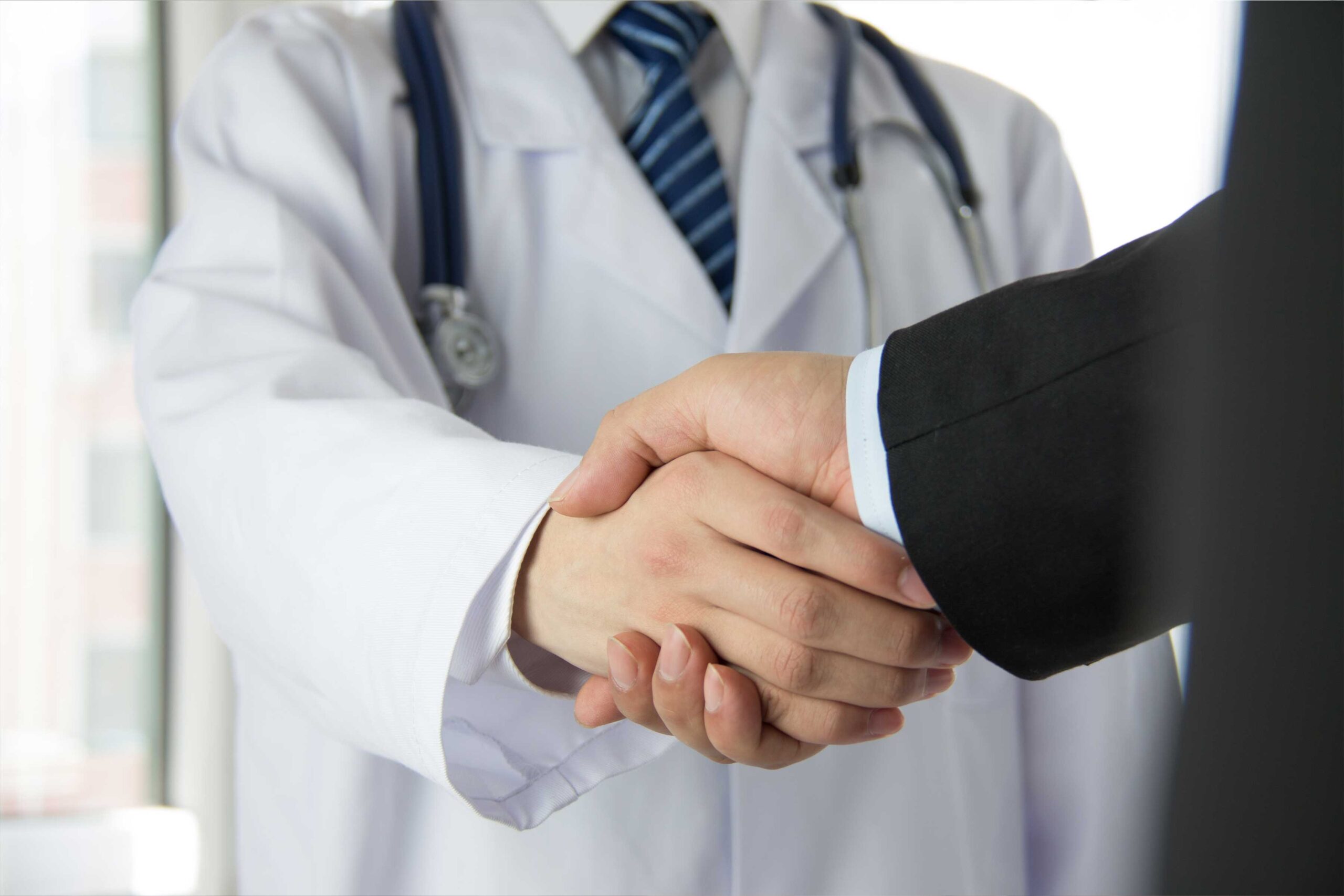 Doctor and business professional shaking hands, symbolizing American SurgiSite’s trusted partnerships with surgery centers.
