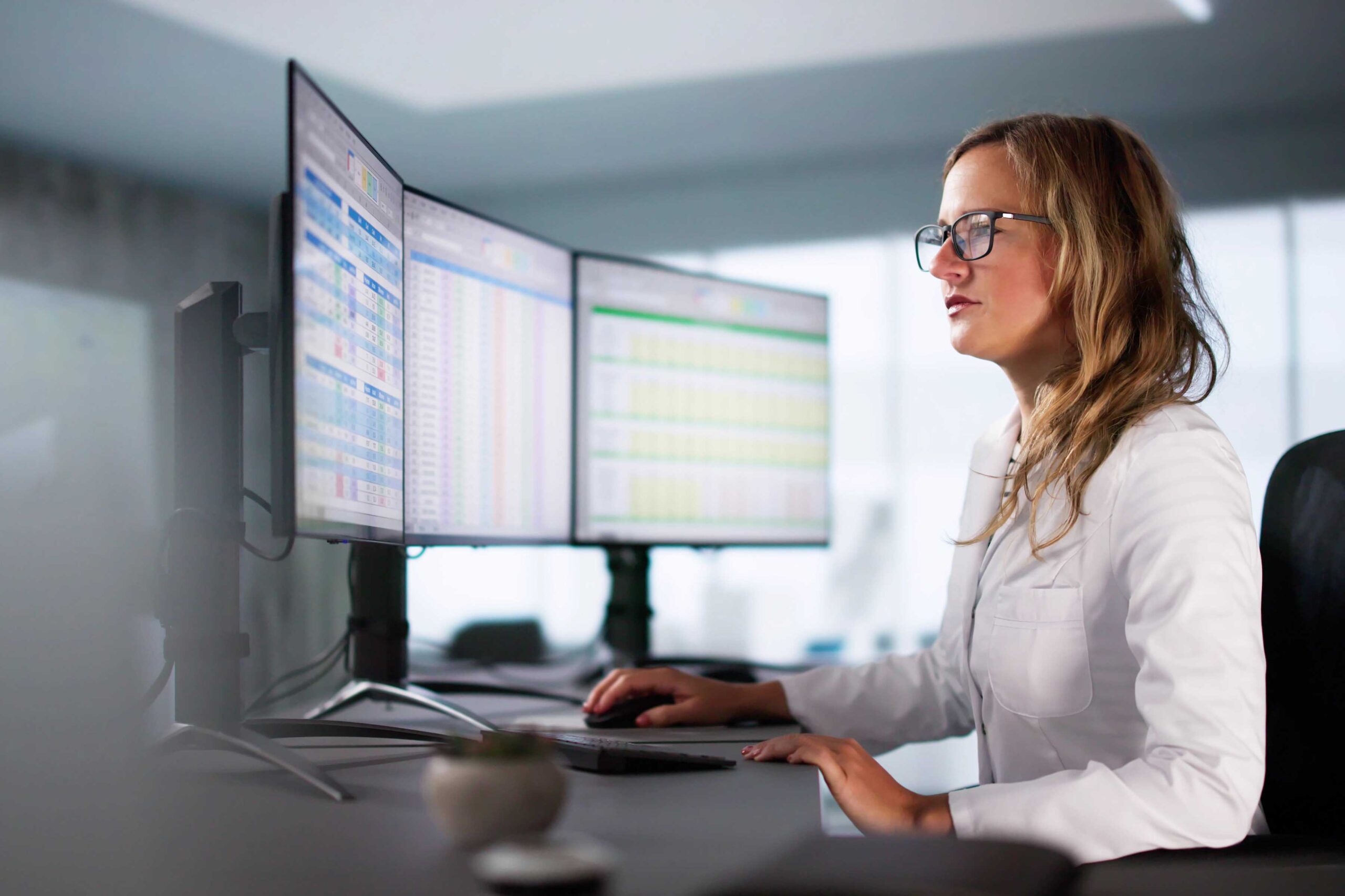 Healthcare professional analyzing data on multiple computer screens, representing American SurgiSite’s focus on analytics and operational oversight for surgery centers.